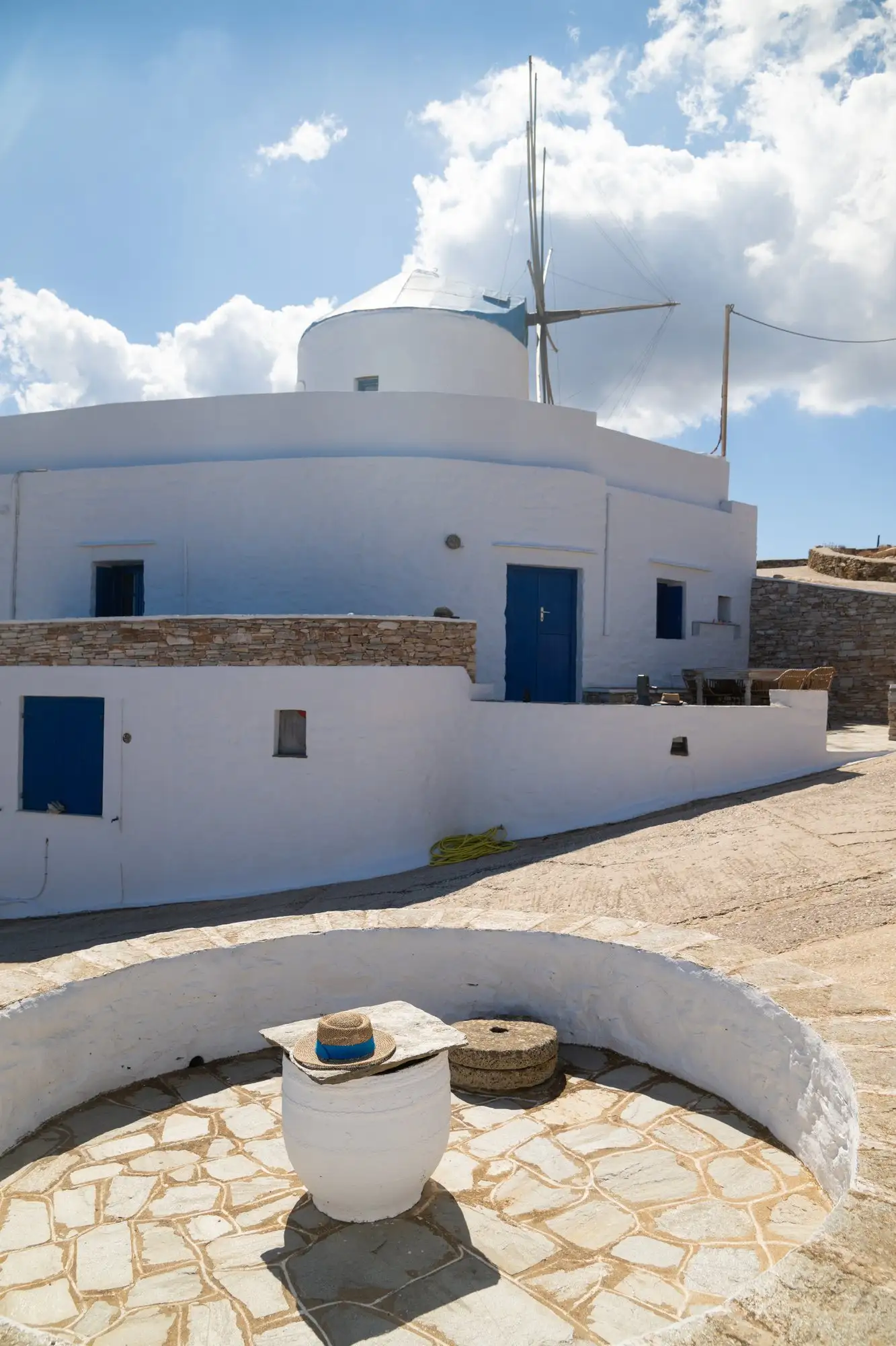 Λευκά κτίρια με μπλε πόρτες και ο ανεμόμυλος πίσω τους