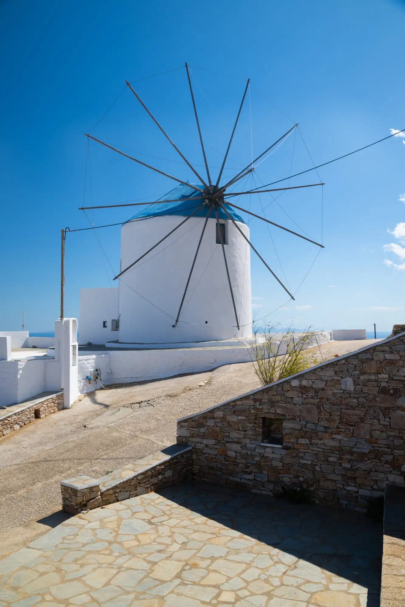Ο ανεμόμυλος του Windmill Villas με τις ακτίνες των πανιών του και τον γαλάζιο ουρανό